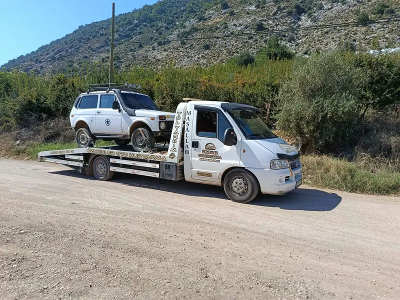 Özmenler Oto Kurtarıcı çekicisi dağ yolu yakınında beyaz arazi aracını taşırken